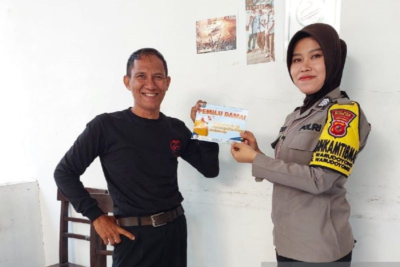 Bhabinkamtibmas Menyebarluaskan Brosur Seruan Pemilu Damai